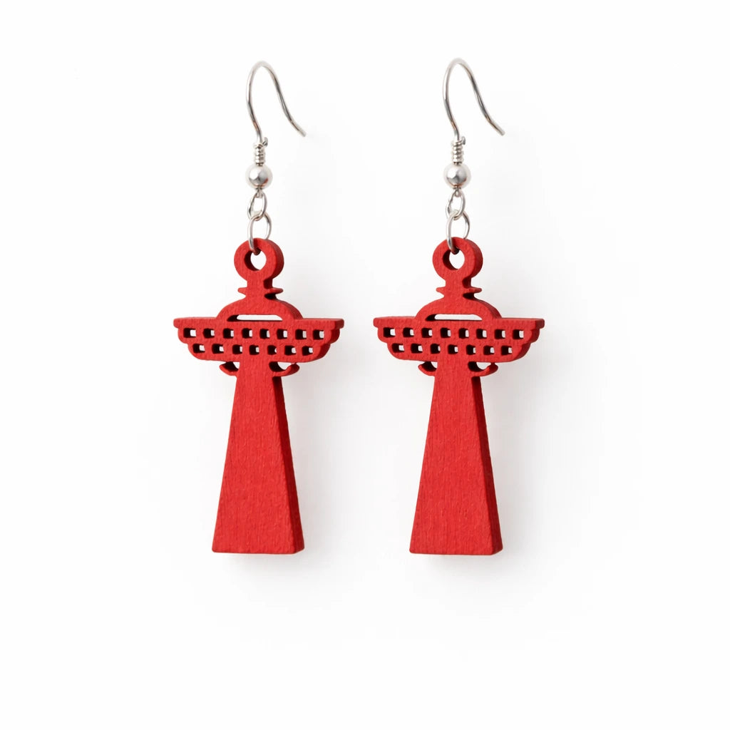 Pari kirkkaanpunaisia, puisia Näsinneula-korvakoruja valkoisella pohjalla – esittelee Toe-Nahka Designin laserleikattua muotoilua ja tasaista väripintaa.